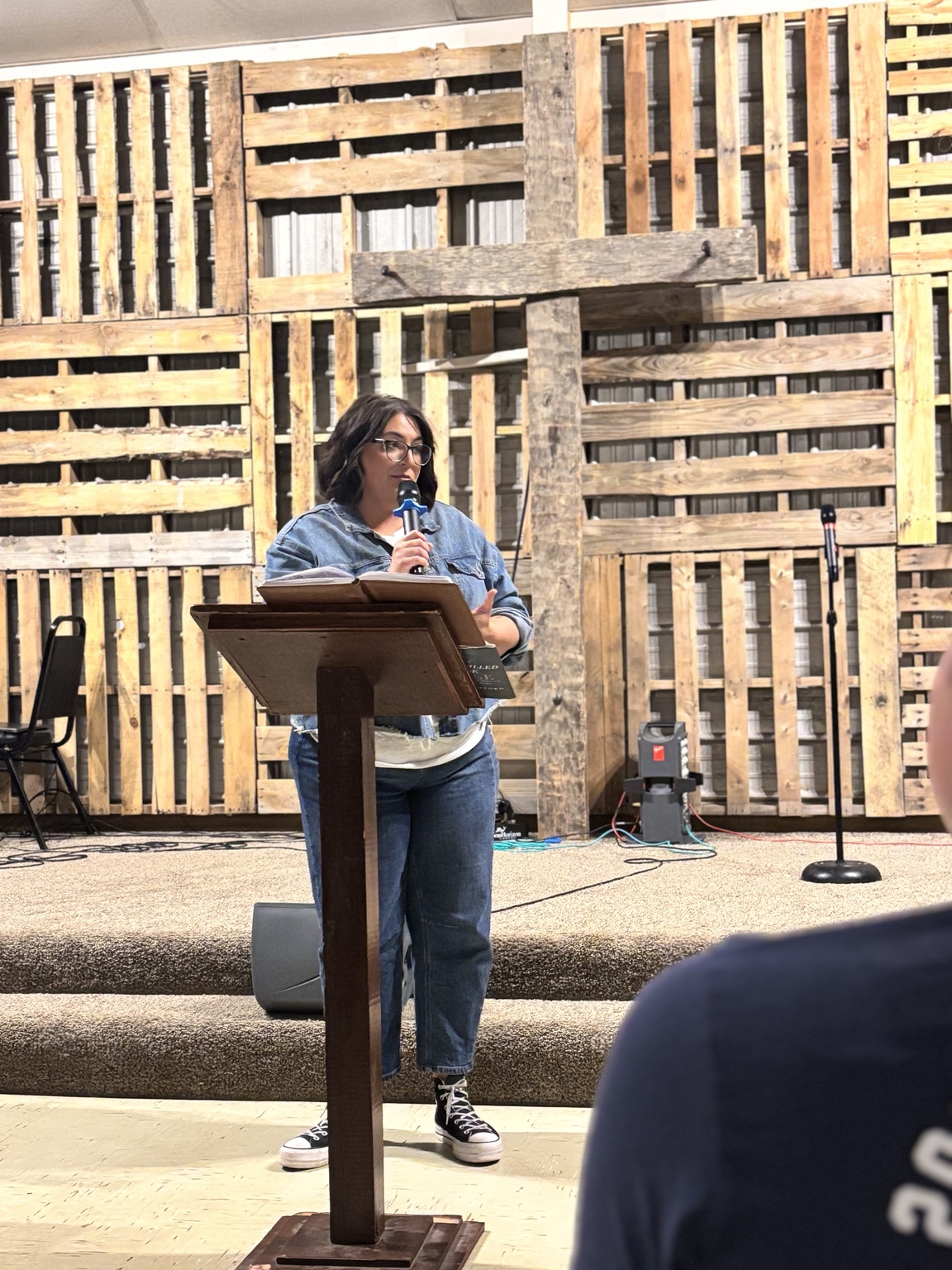 Chelsea teaching from Scripture in front of a wooden cross
