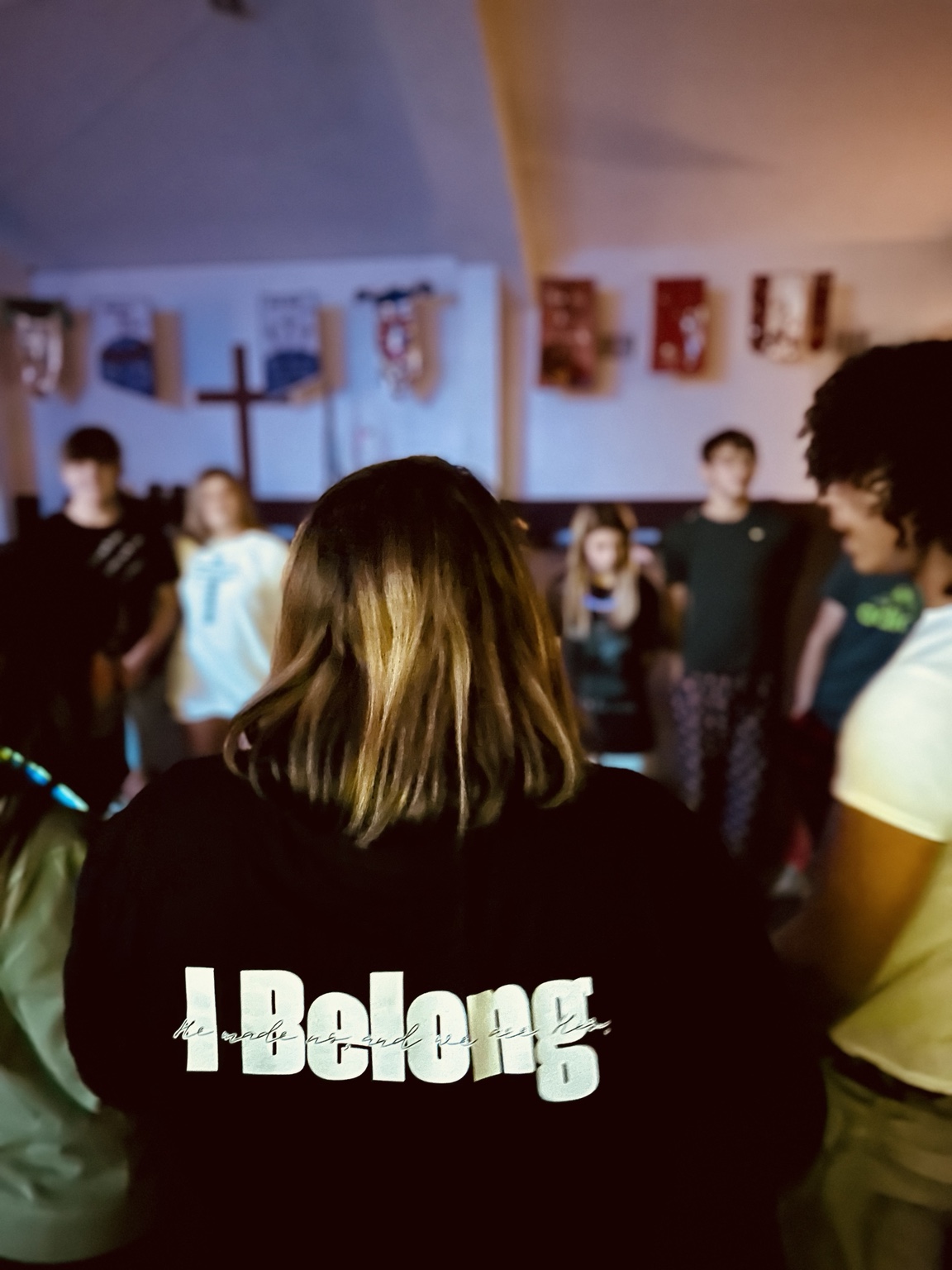 Leader wearing an I Belong shirt with students gathered in a circle