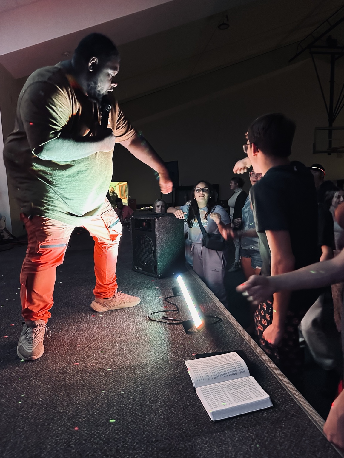 Speaker ministering to students with an open Bible on the stage
